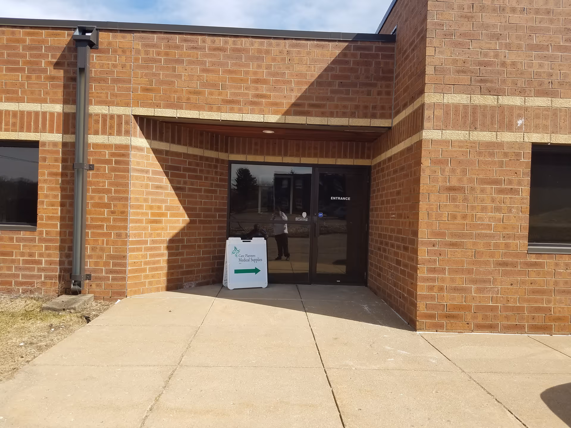 Brick exterior entrance of Care Planners facility with glass doors and a sidewalk sign