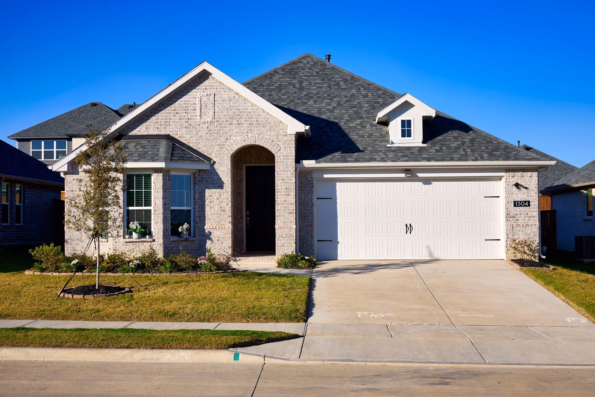 Front view of a modern brick home with a two-car garage and manicured lawn.