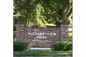 Exterior brick sign reads Pleasantview Home with shrubs in front of the building.