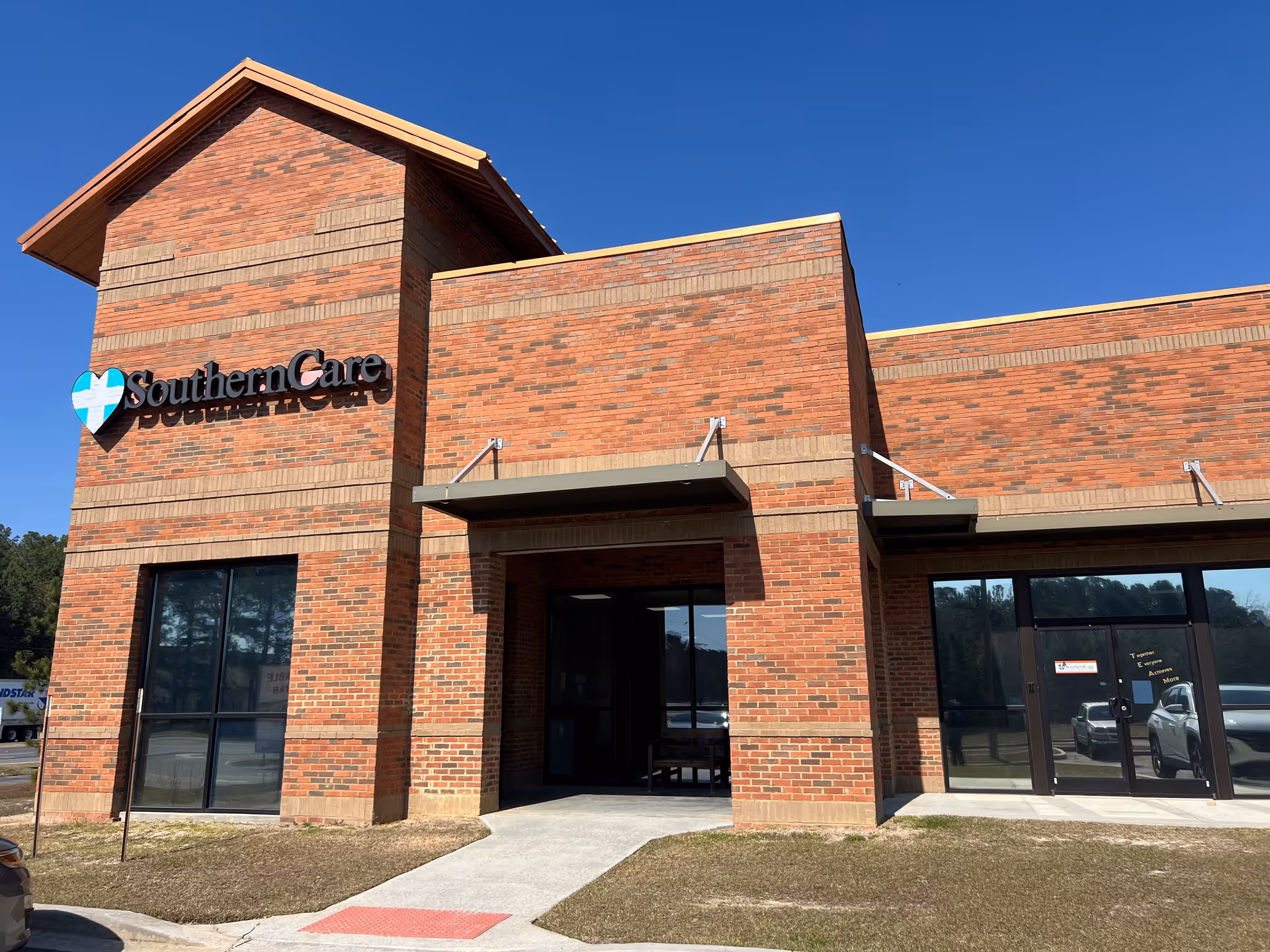 Brick Regency SouthernCare building exterior with glass doors and clear blue sky.