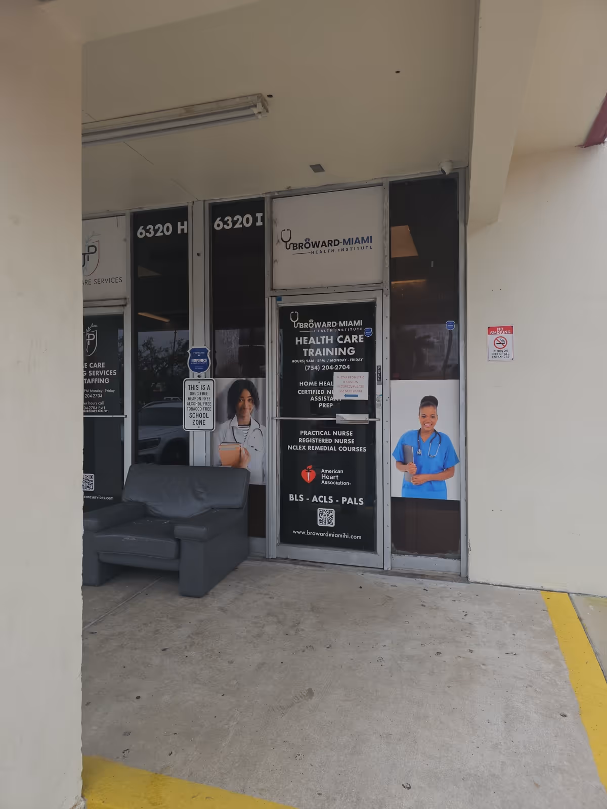 Storefront entrance with posters advertising healthcare training; a gray couch sits outside.