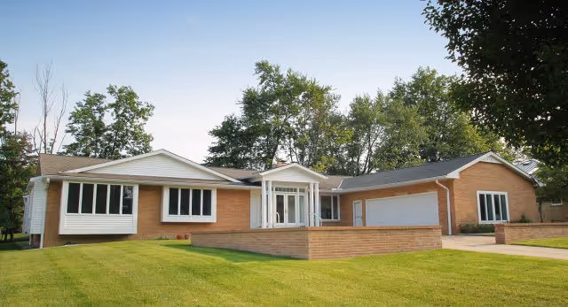 Single-story brick senior living facility with a white entrance and well-kept lawn.