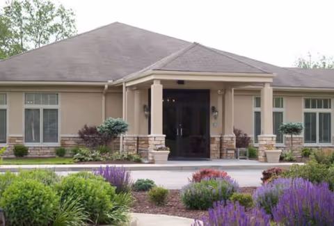 Front view of The Greenbriar Nursing Center entrance with shrubs and purple flowers.