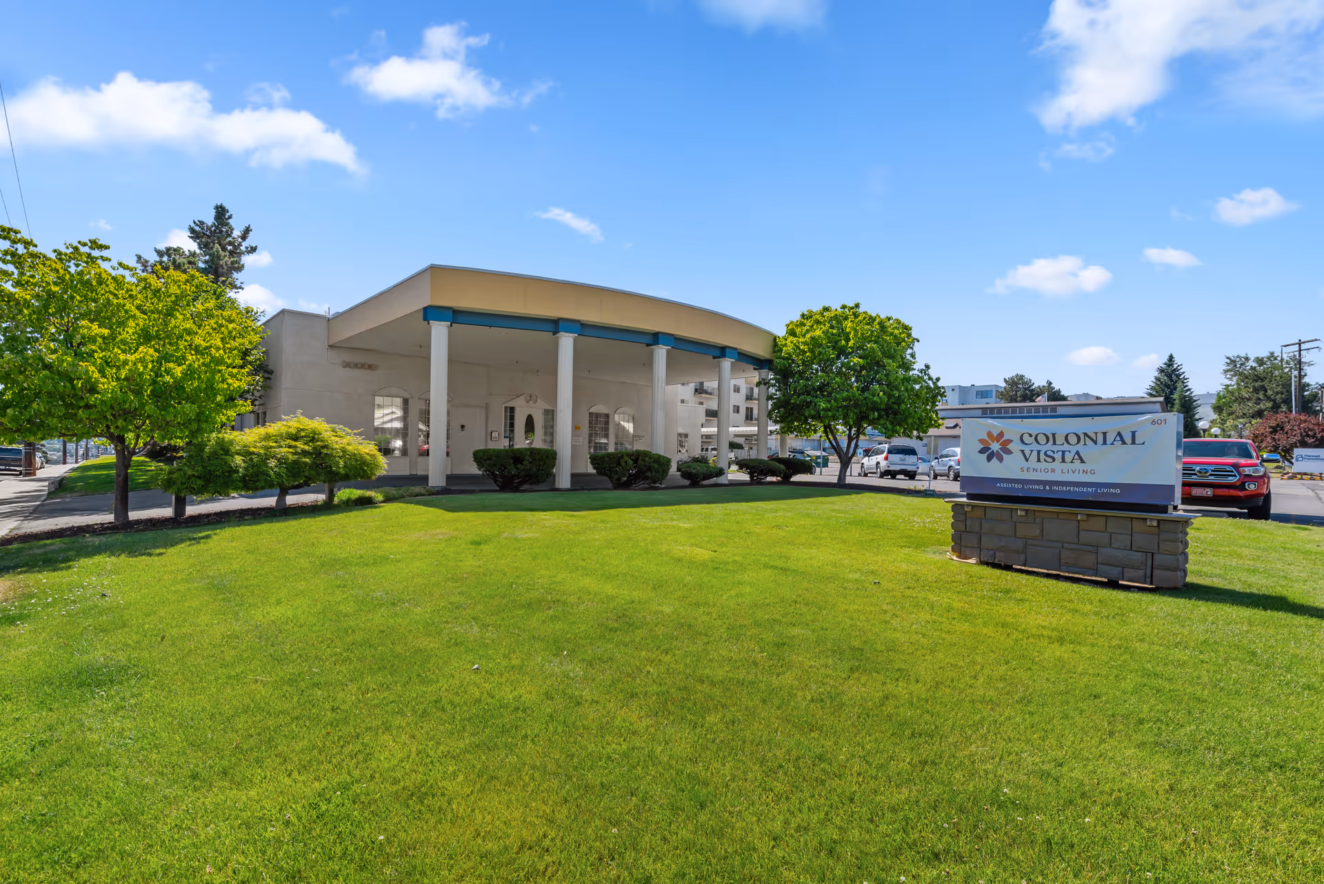 Front lawn and entrance of the Colonial Vista Senior Living building with a sign on the grass.