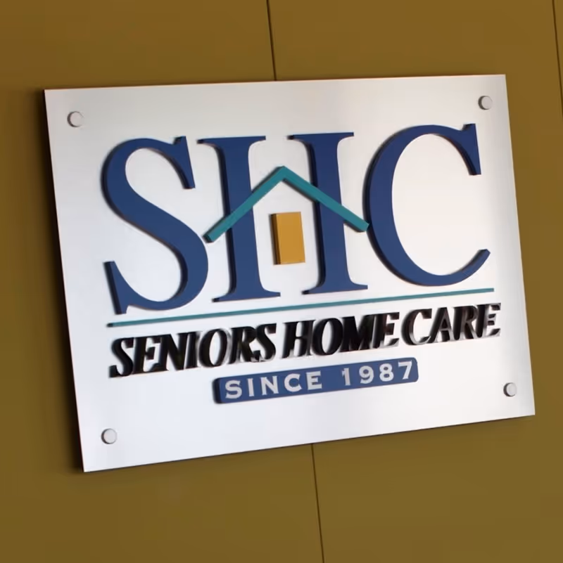 White SHC Seniors Home Care sign mounted on a yellow wall.