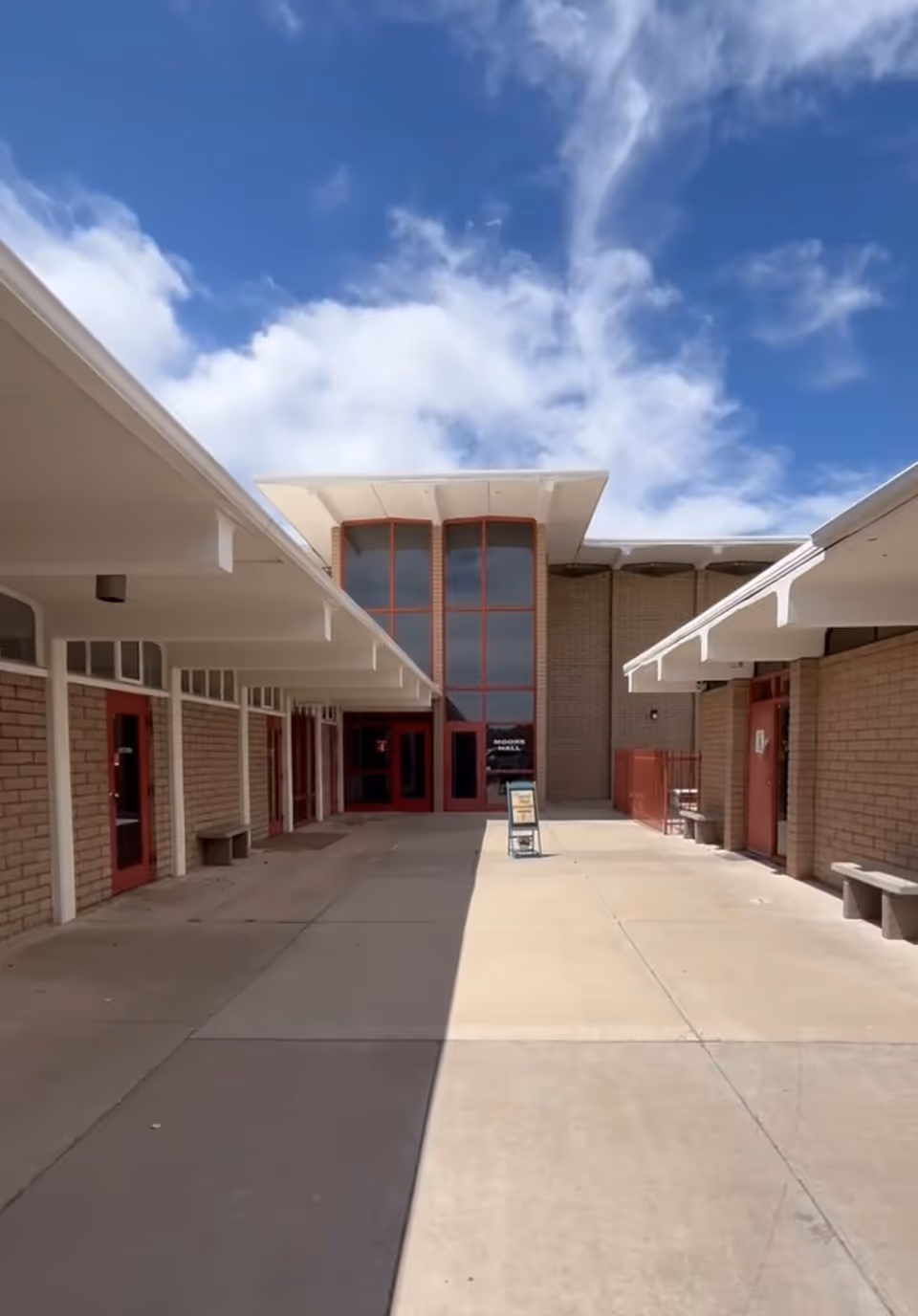 Exterior walkway flanked by brick walls leads to TLC Services LLC entrance.