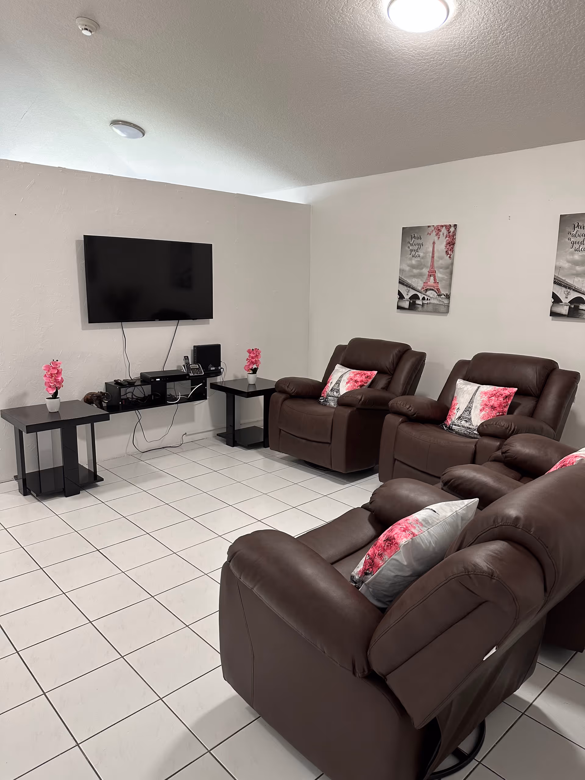Brown leather recliners surround a wall-mounted TV in a bright living room.