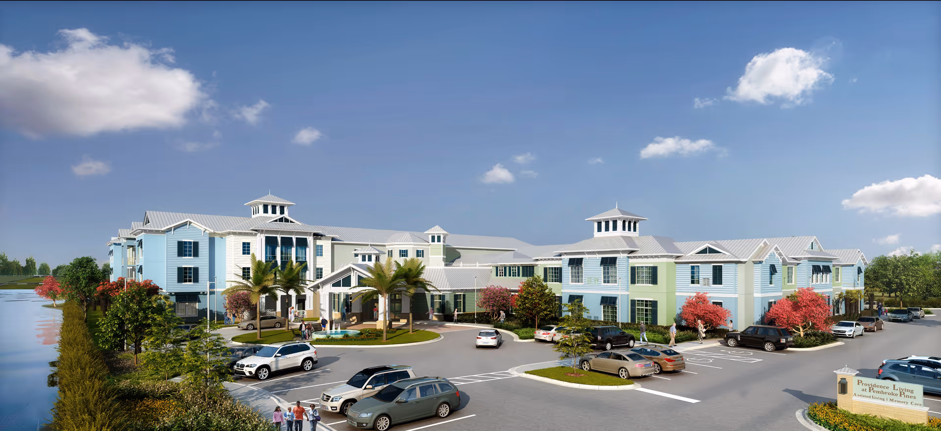 Front exterior of a two-story pastel-colored senior living facility with a circular drive, parked cars, landscaping, and a lake to the left.