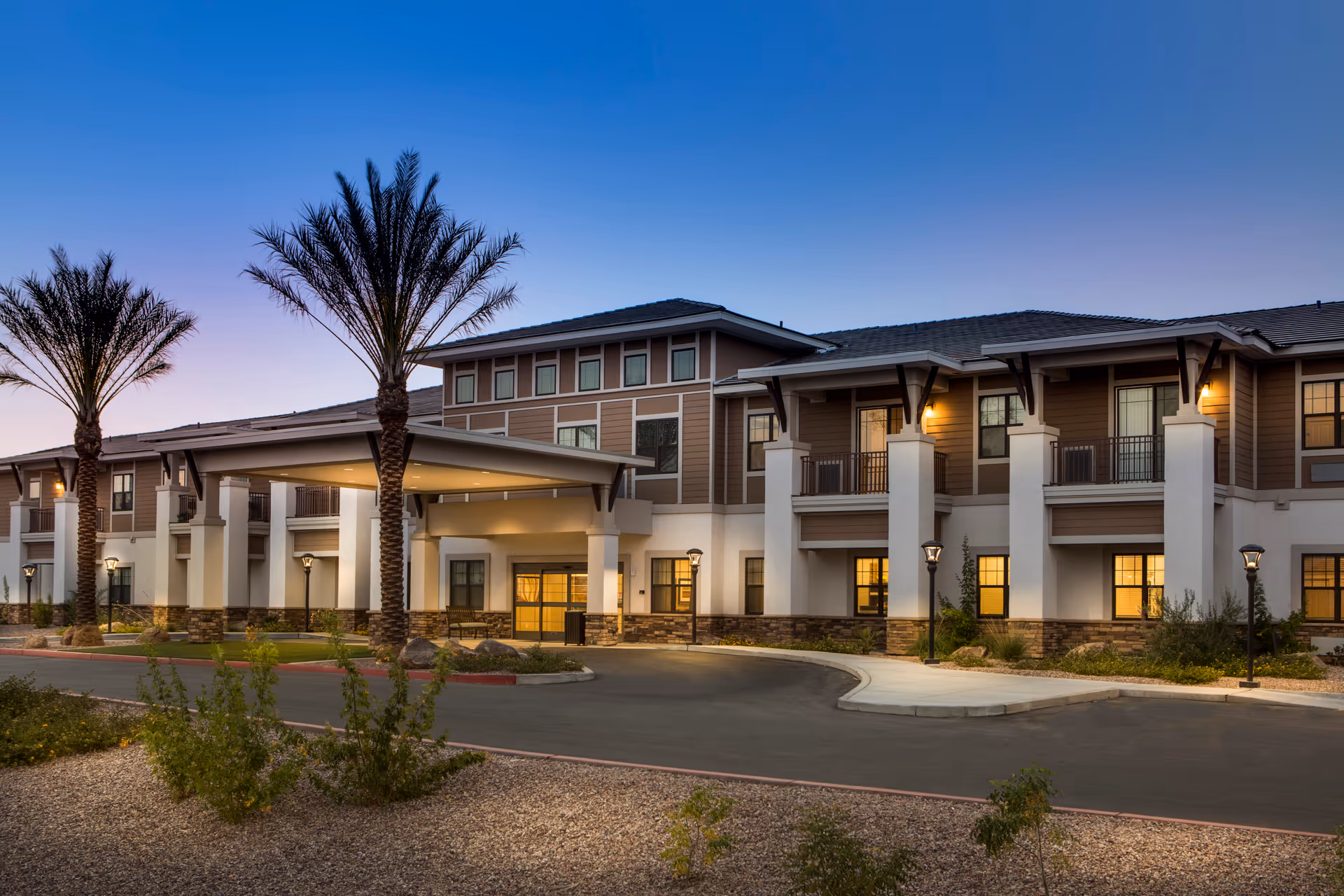 Exterior view of Savanna House senior living facility with porte-cochere and palm trees.