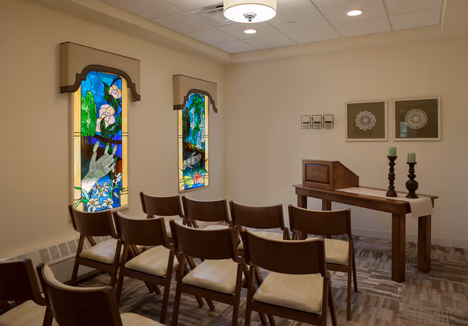 Chairs arranged in a small chapel with stained glass windows and an altar.