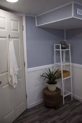 Blue-walled interior corner with towel on the door and white shelving.