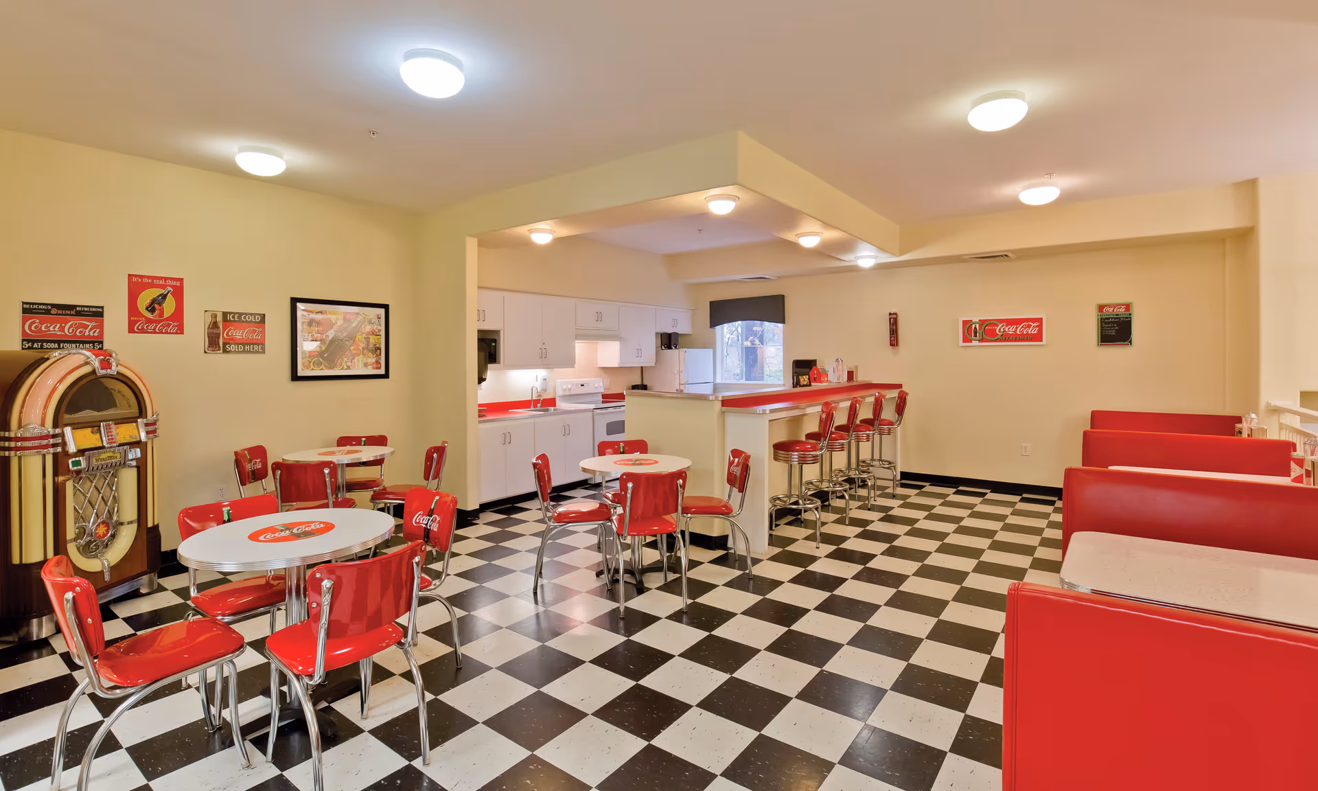Retro diner-style dining area with red booths, checkered floor, and counter stools.