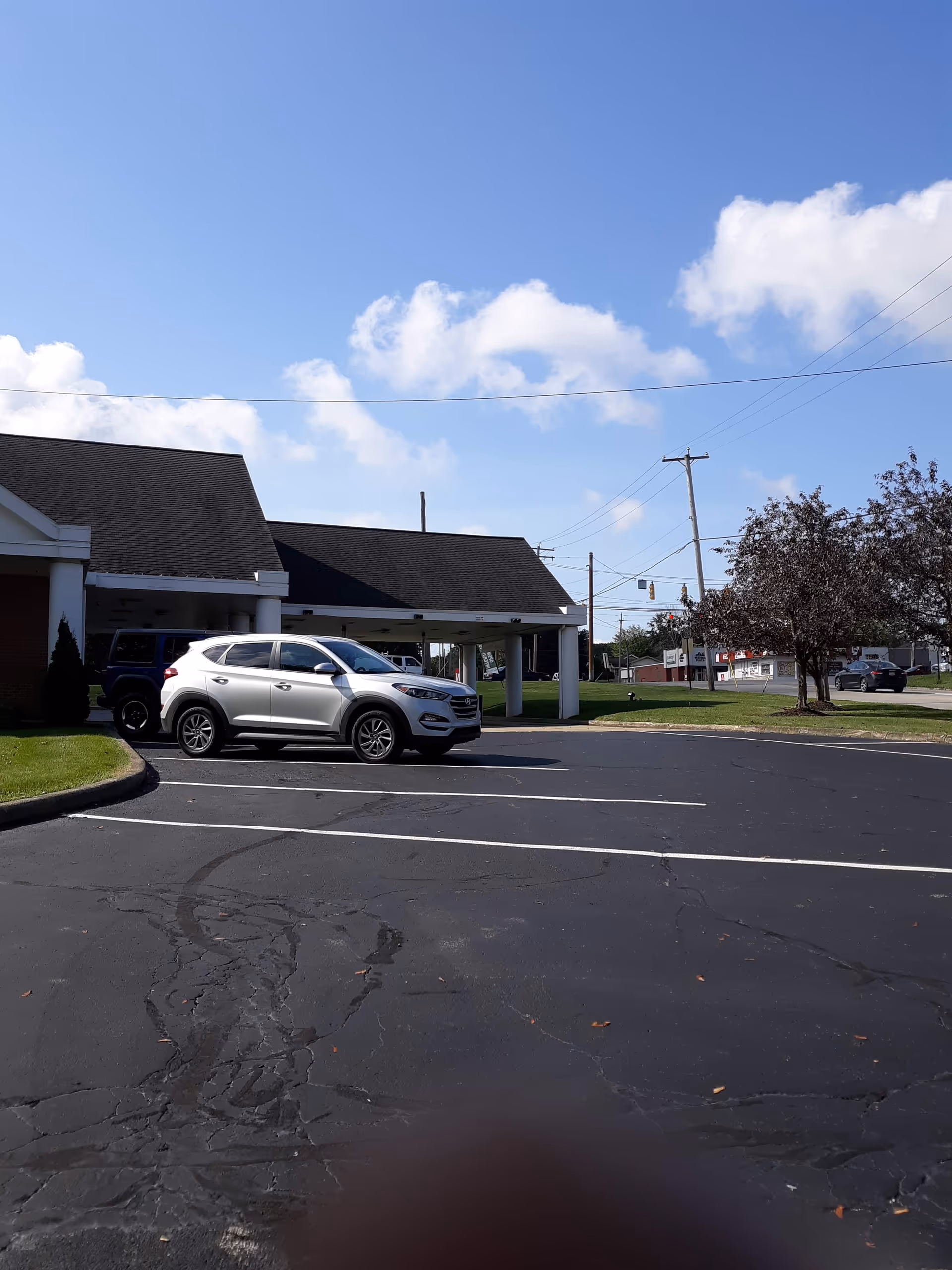 Exterior view of a senior living facility with a parking lot and a white SUV