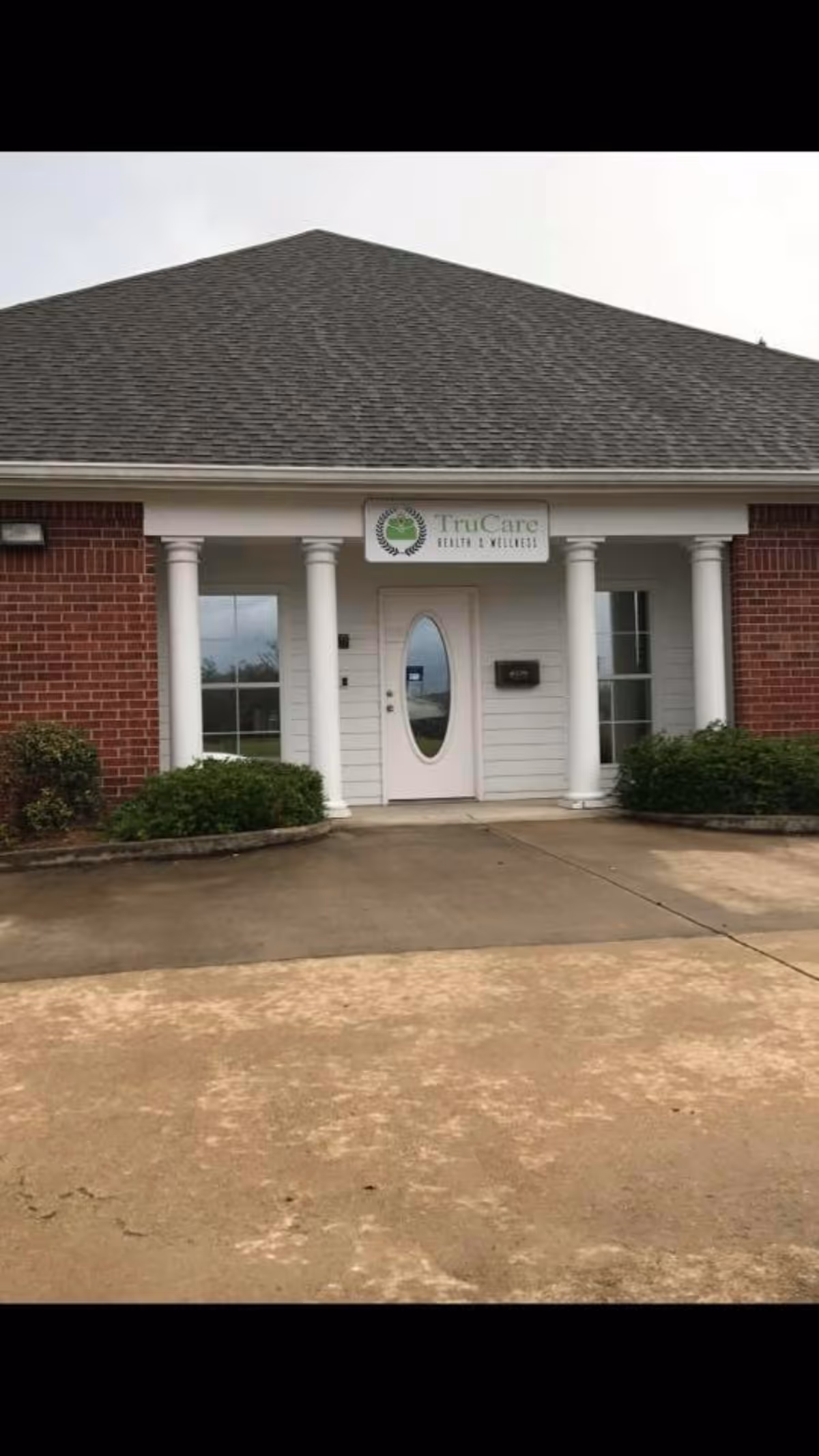 Front entrance of TruCare Health and Wellness facility with white columns and sign.