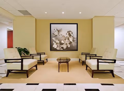 Six cream chairs are arranged around a glass coffee table in a lobby lounge.
