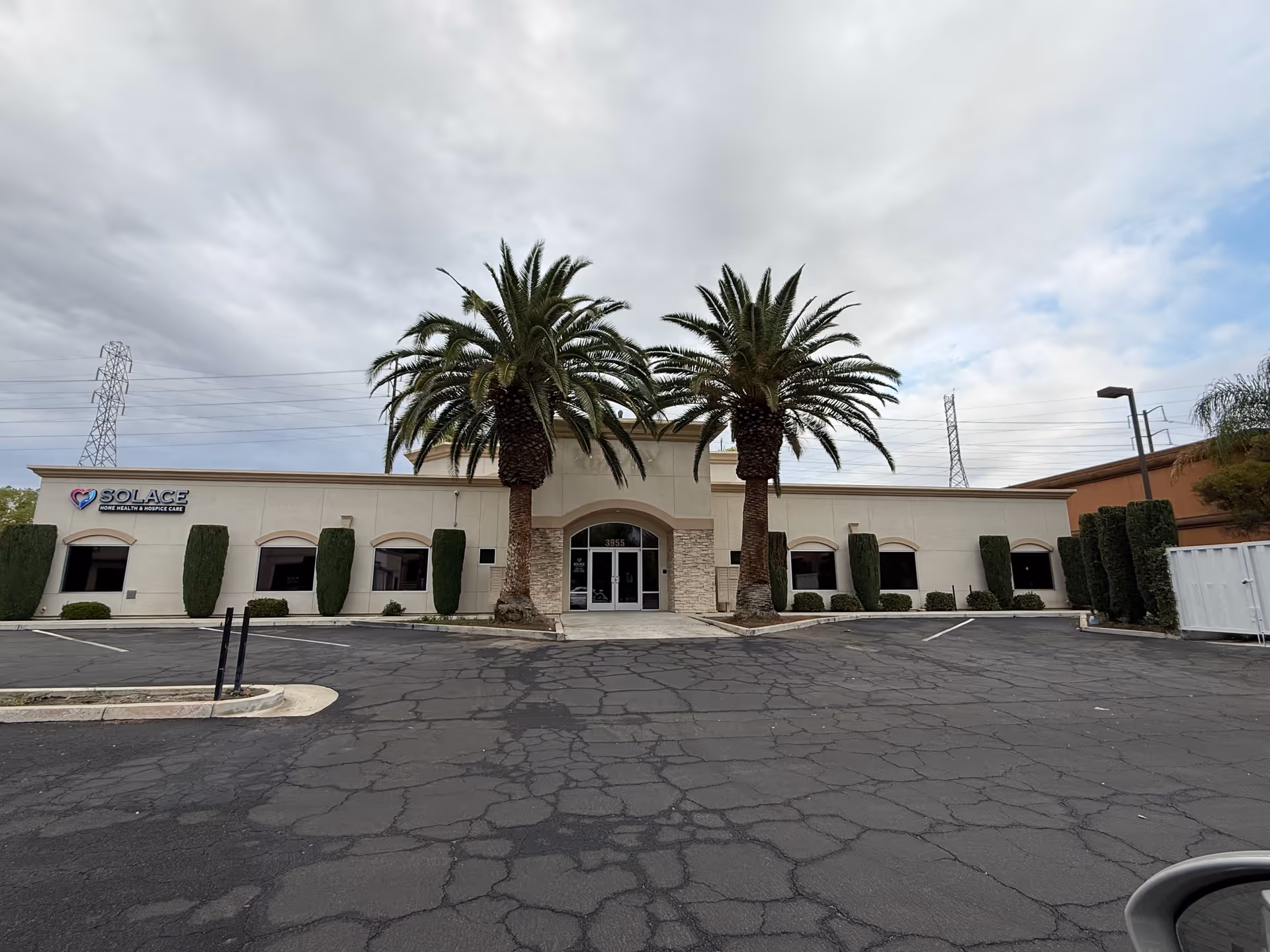 Front view of Solace home health and hospice care building with two palm trees.