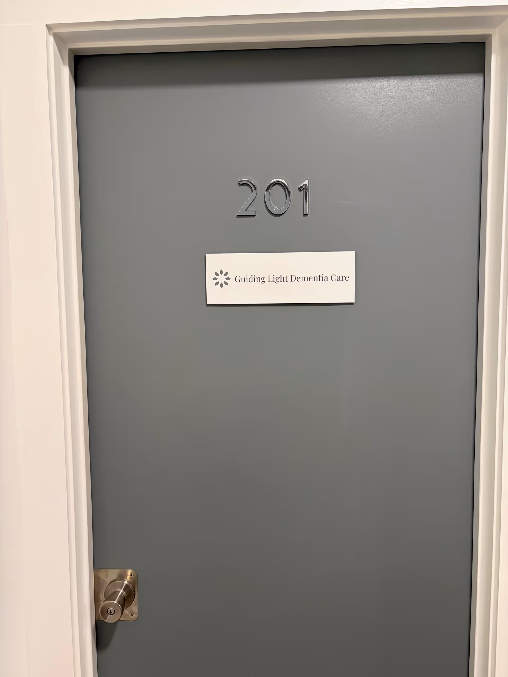 Gray interior door labeled 201 with a sign for Guiding Light Dementia Care.