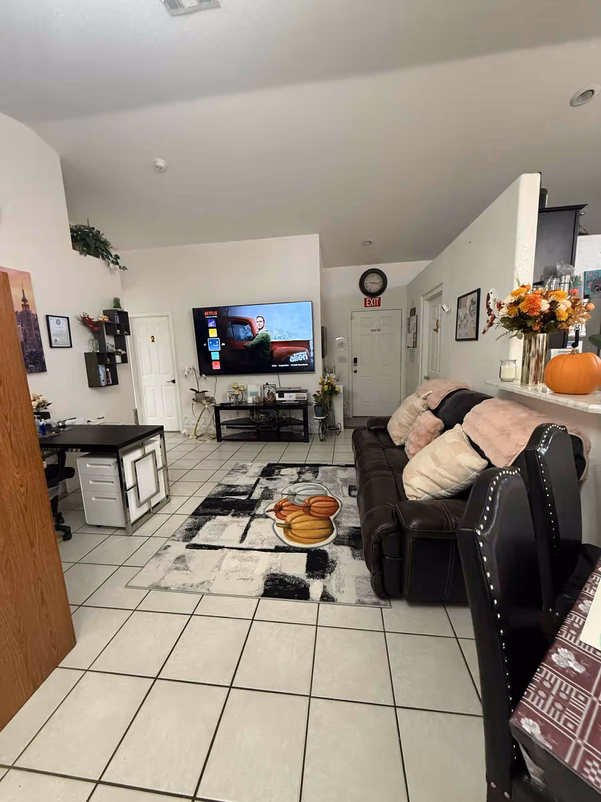 Living room at a senior facility with TV, sofa, tiled floor, and pumpkin decor.