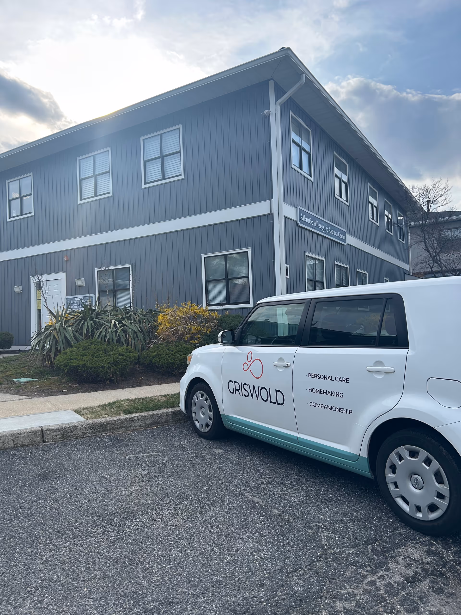 Blue two-story senior living facility with a Griswold van parked outside.