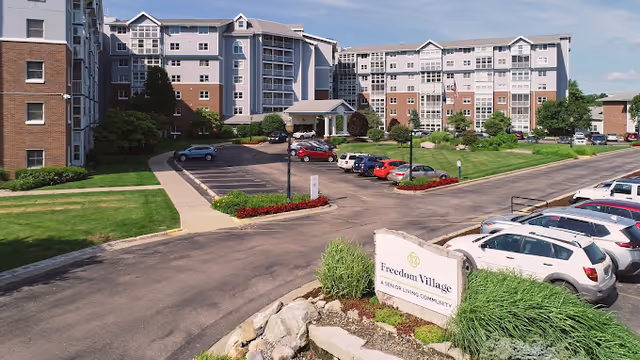A large Freedom Village senior living campus with a parking lot and entrance sign.