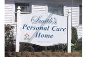 An outdoor sign reads Smith's Personal Care Home in front of a white house.