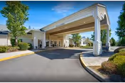 Covered entry with circular driveway and manicured landscaping at a retirement community.