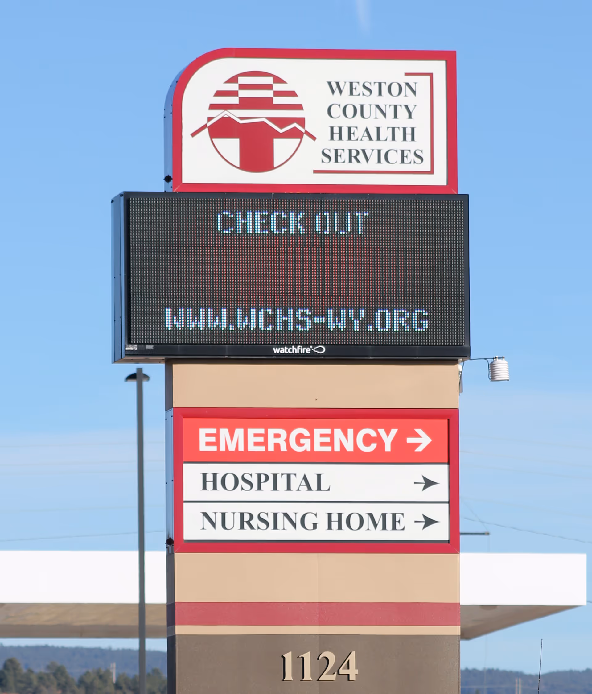 Exterior sign for Weston County Health Services with emergency directions.
