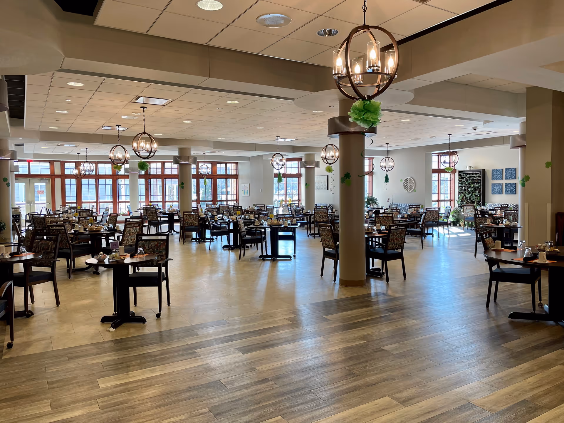 A spacious senior dining room with many tables, chairs, and circular pendant lights.