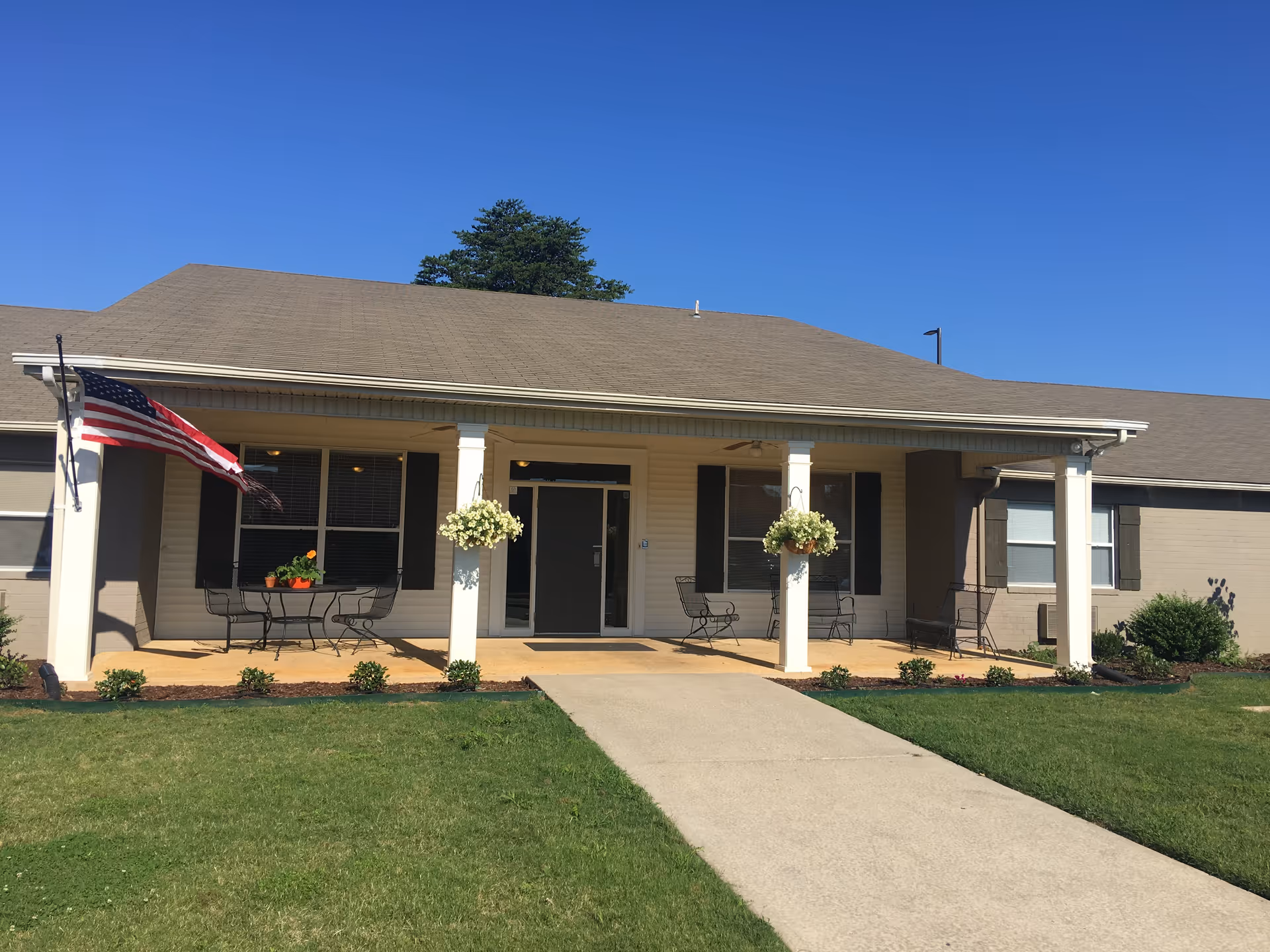 Front view of Limestone Lodge: single-story building with porch, columns, planters, and outdoor seating.