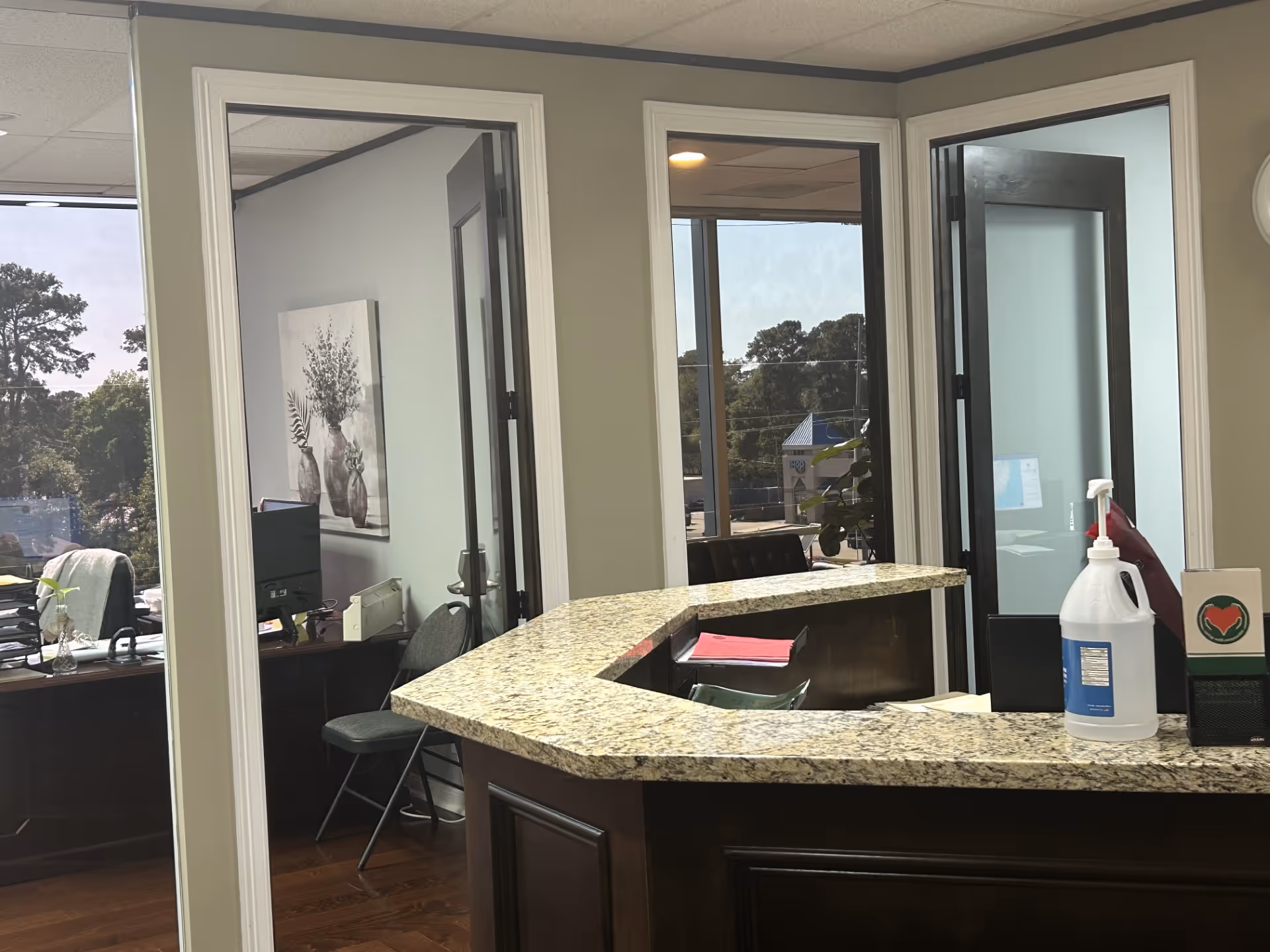 Reception area with granite counter, glass doors, office spaces, and plant decor.
