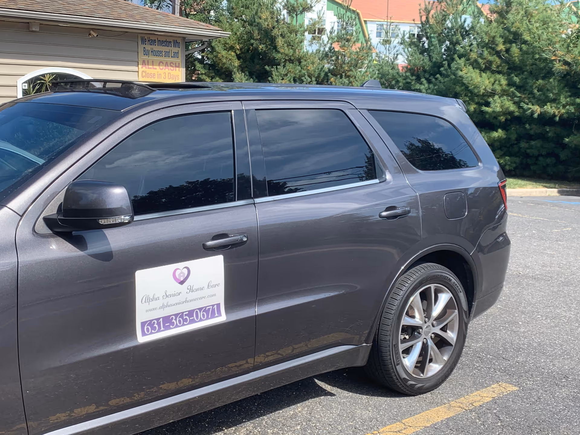 Gray SUV with Alpha Senior Home Care sign parked in a lot beside a facility