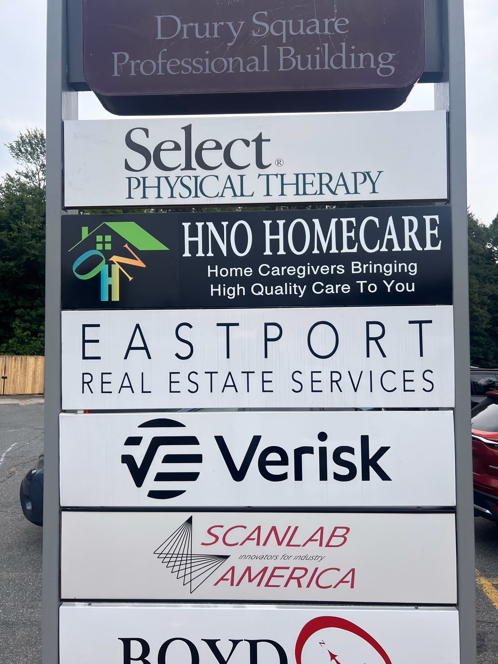 Tall outdoor signboard displaying HNO Homecare alongside other business names