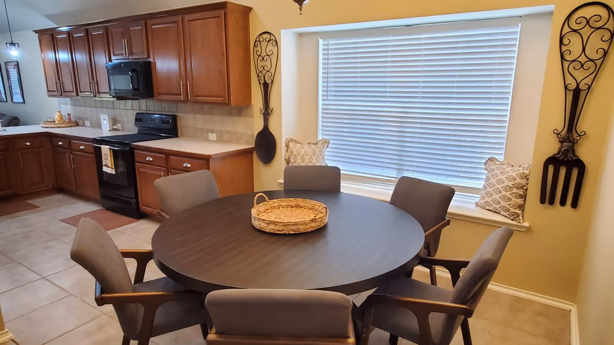 Round dining table with six chairs in a kitchen-dining nook.