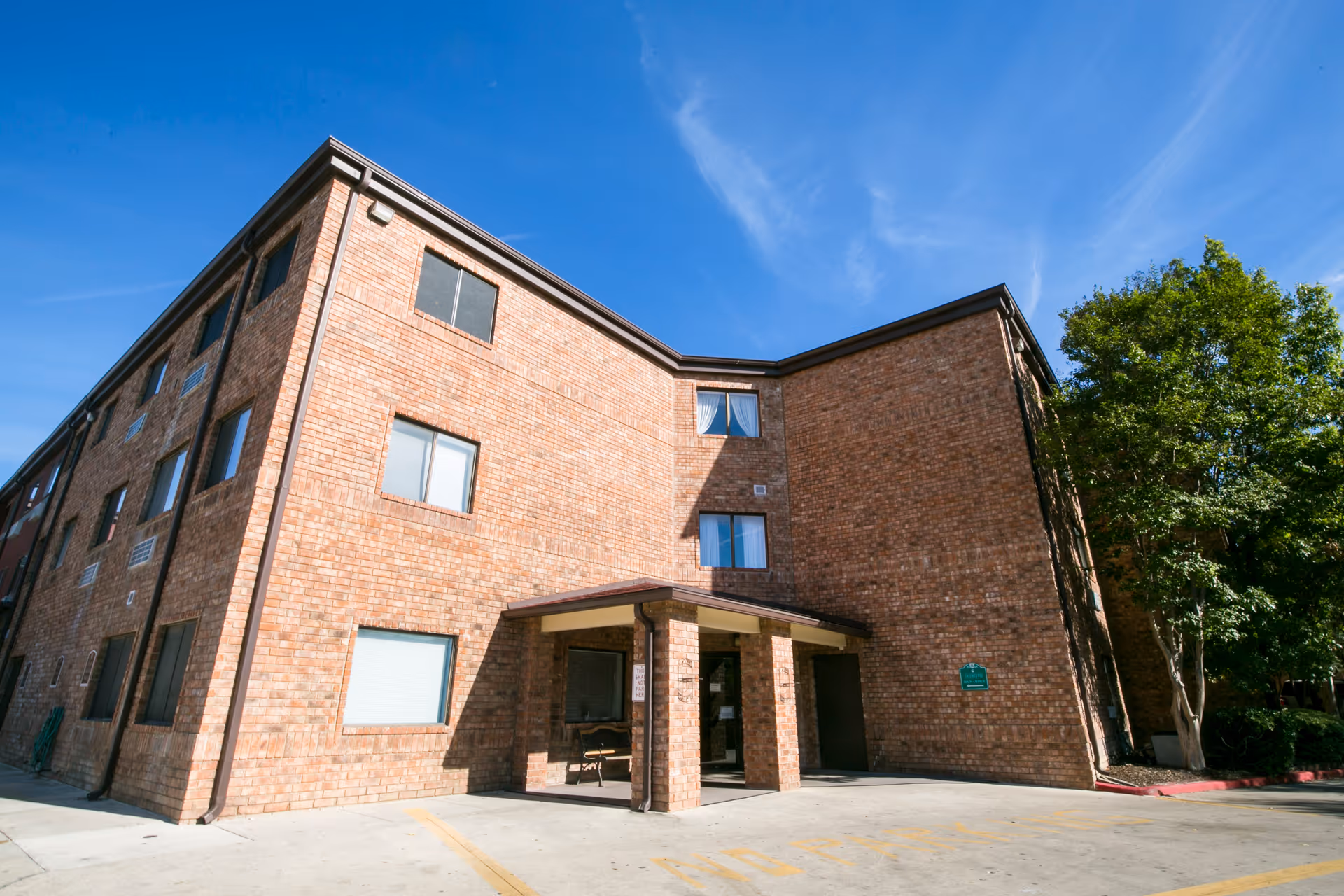 Camino Real senior living facility exterior with entrance canopy and trees.