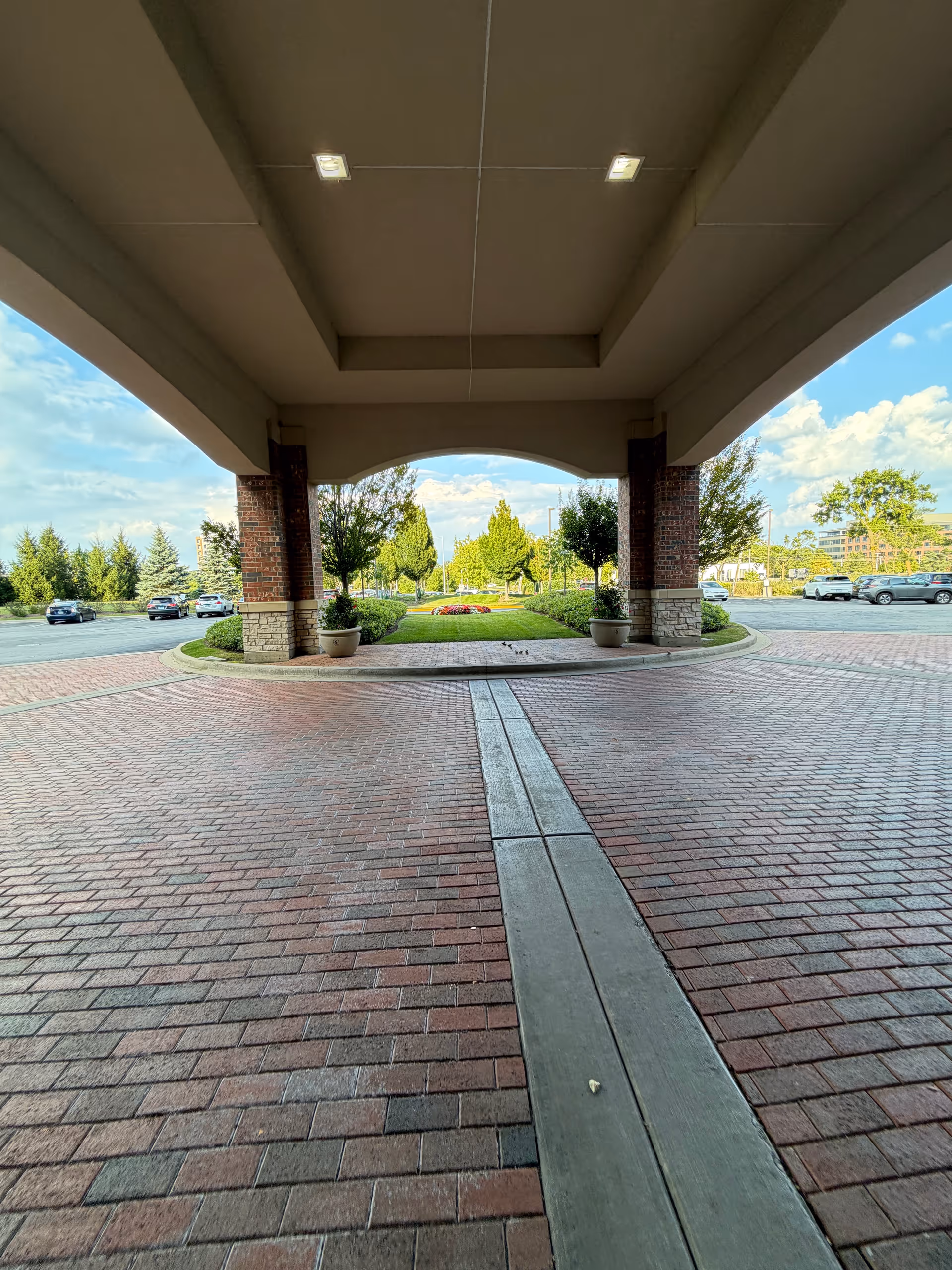 Covered porte-cochère entrance with brick columns and circular driveway.