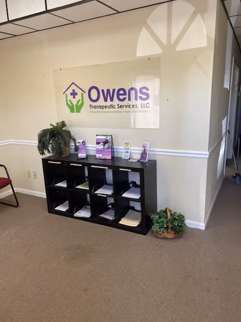 Interior lobby with Owens Therapeutic Services sign, brochure rack, plants, and seating.