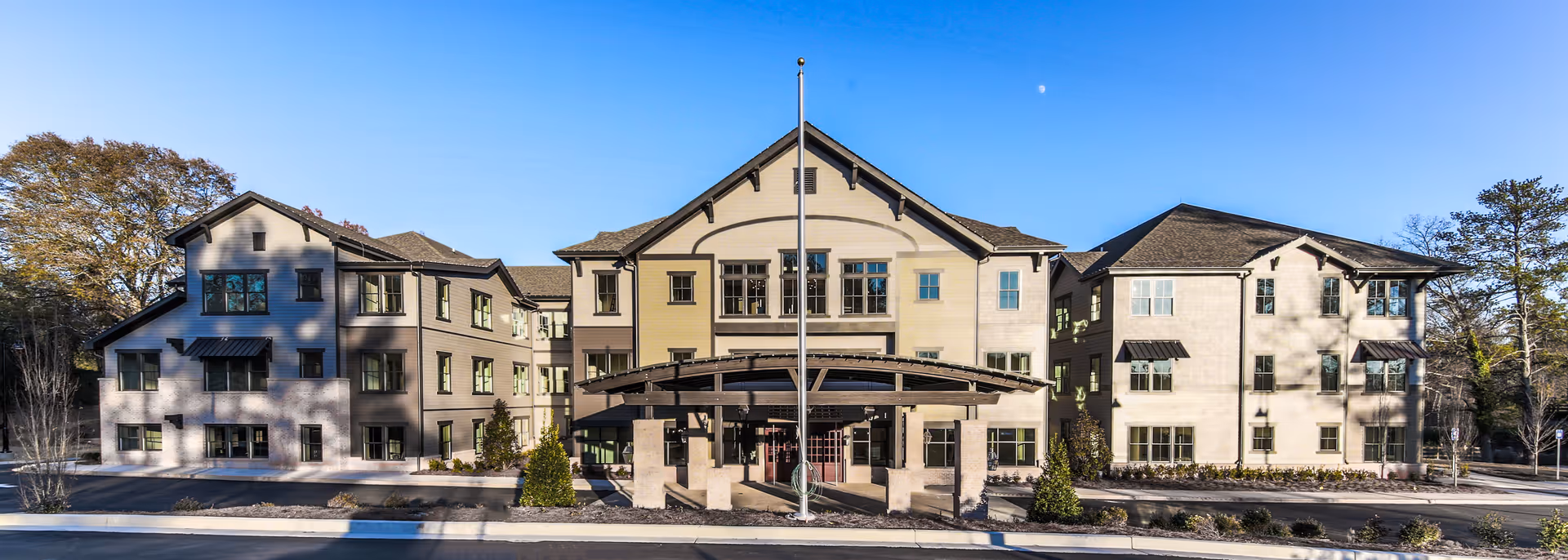 Front view of a multi-wing senior living facility with a central porte-cochère.