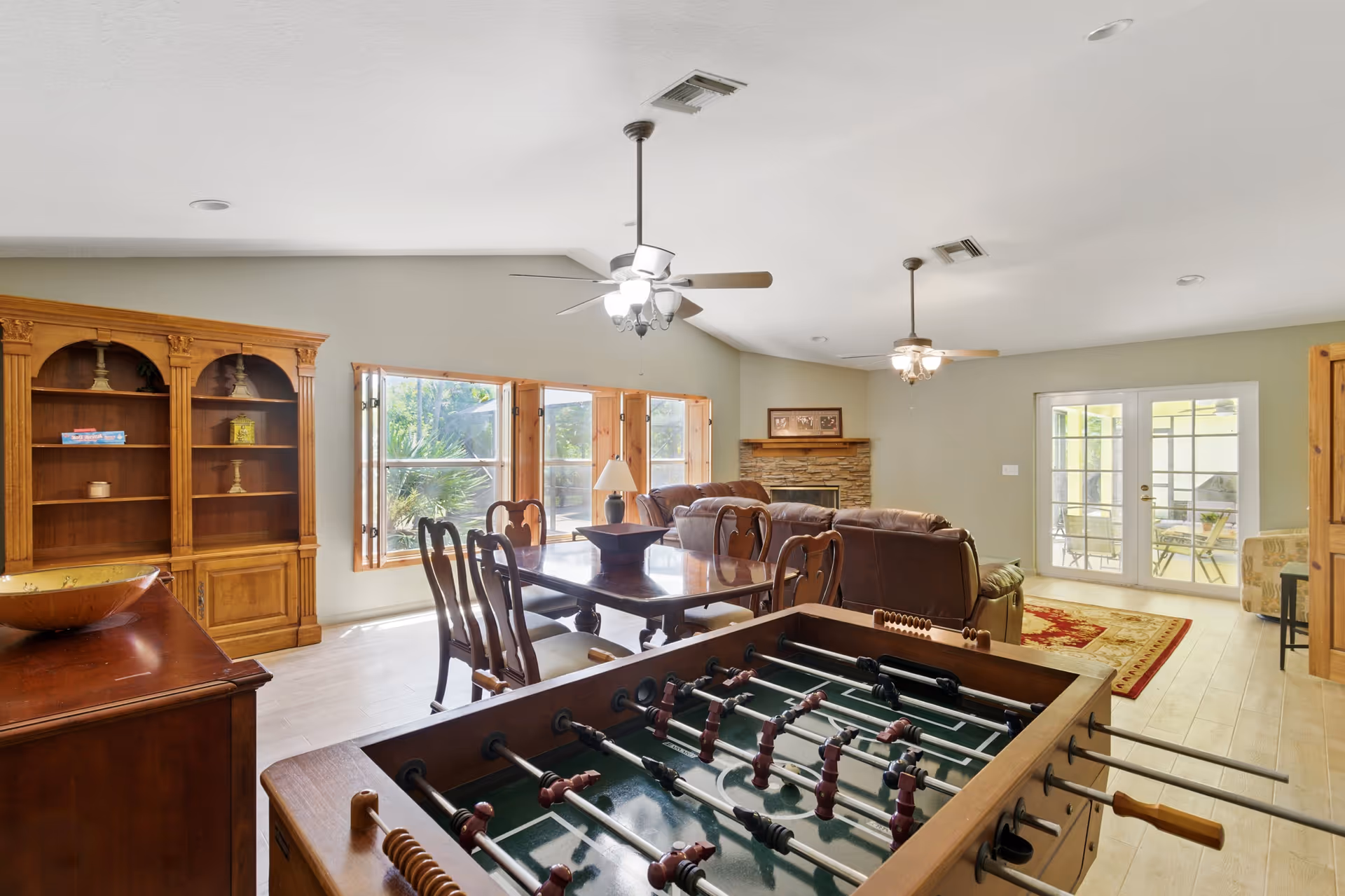 Interior living room with foosball table, seating, fireplace, windows, and French doors.