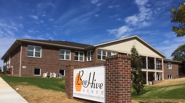 Exterior view of a brick senior living facility with a Bee Hive Homes sign.