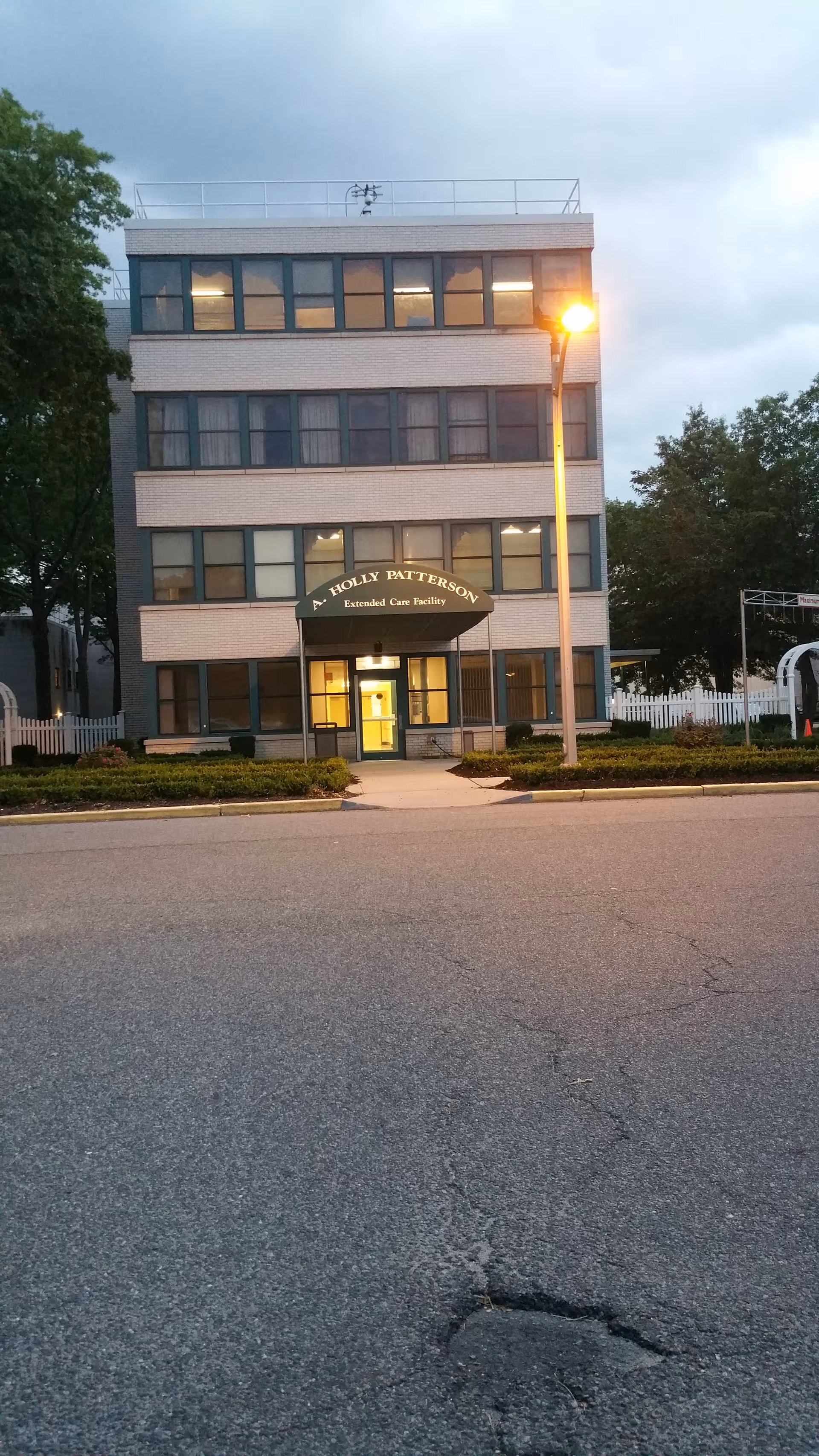 Three-story brick facility with curved entrance awning reading A. Holly Patterson Extended Care.