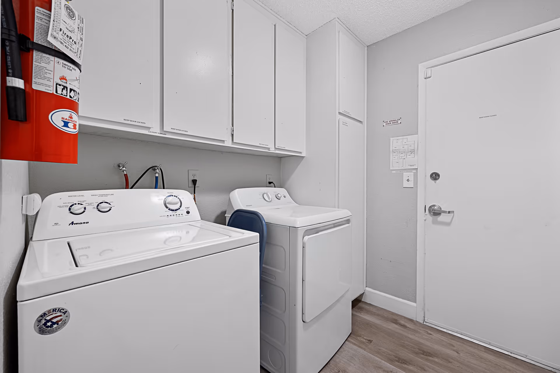 Laundry room with white washer, dryer, and overhead cabinets.