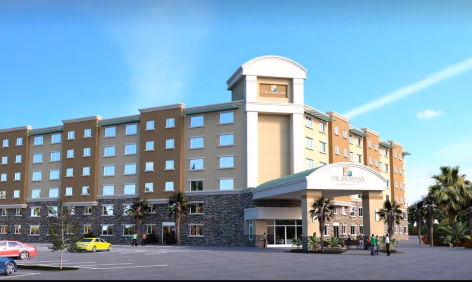 Meridian at Westwood senior living building with curved entrance, stone base, and palm trees.