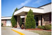 Exterior view of Lakeland Rehabilitation and Health Care Center entrance with brick columns and shrubs.