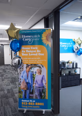 Lobby area with promotional banner, balloons, and a reception counter inside a Homewatch CareGivers office.
