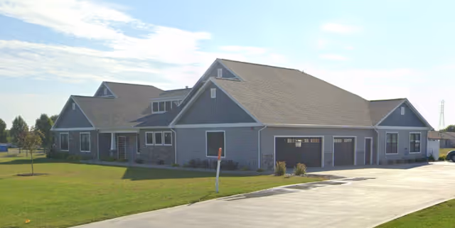 Exterior view of a blue, single-story senior living facility with a driveway and lawn.