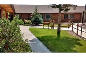 Brick senior living facility exterior with a walkway, green lawn, and a deer sculpture.