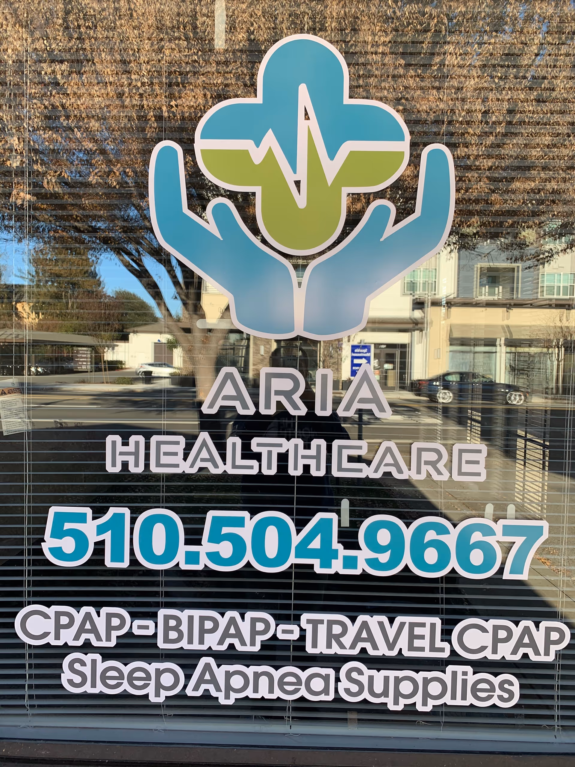 Aria Healthcare logo and phone number on a glass storefront window.