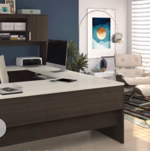Modern reception area with desk, computer, printer, plants, and framed artwork indoors.