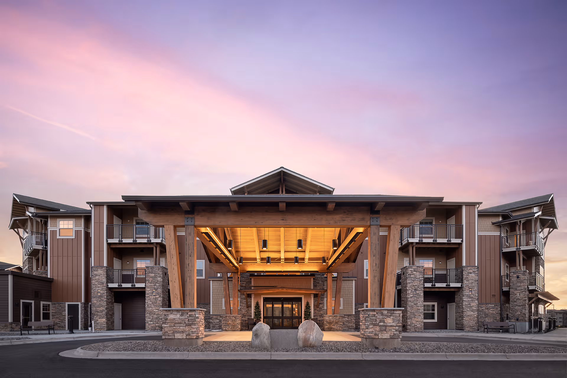 A modern senior living facility exterior with a grand wooden porte-cochère entrance.