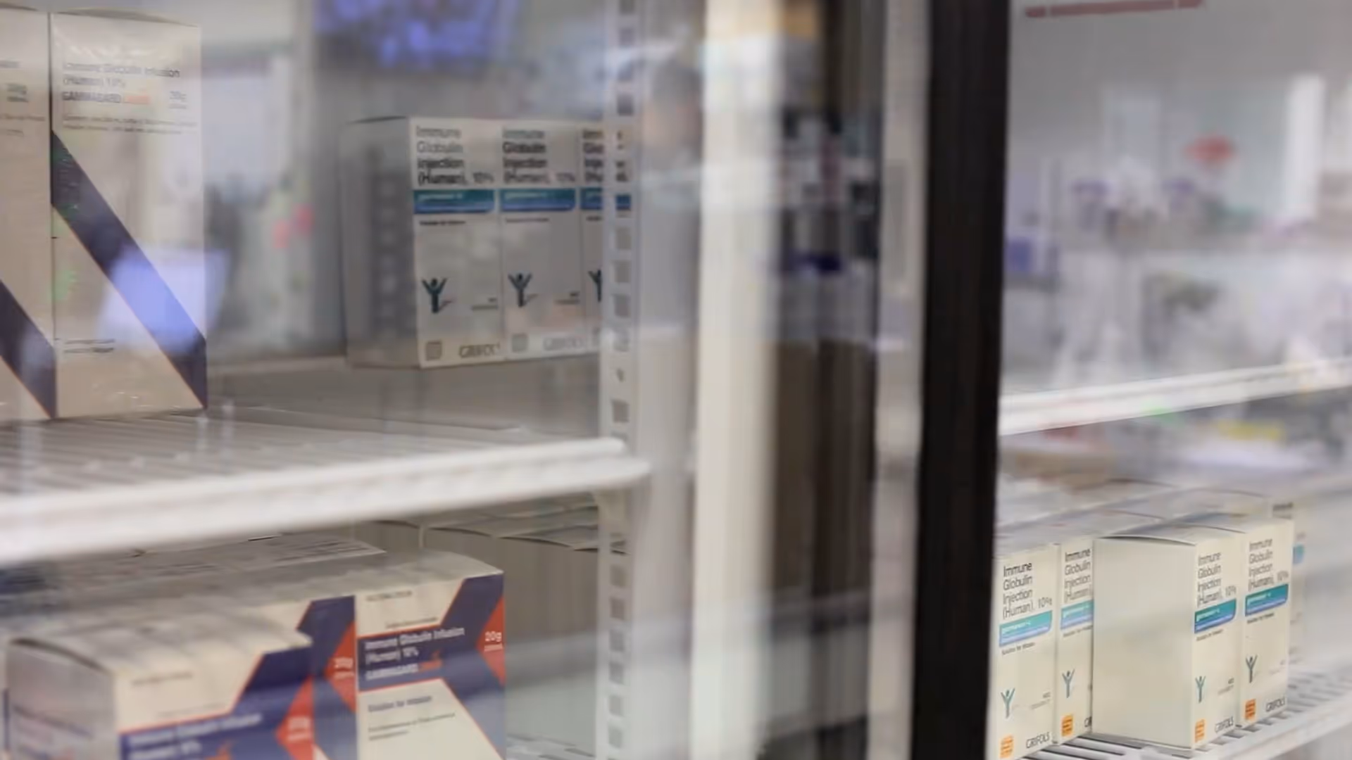 Refrigerated medical storage with boxed vaccines and supplies on shelves.